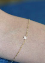Sb Studio Fleur charm bracelet in 14k yellow gold with a delicate flower charm featuring white topaz gemstones.