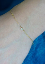Sb Studio 14k yellow gold cable chain bracelet featuring a delicate bezel-set heart-shaped opal charm on wrist.
