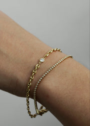 Hand wearing a gold bracelet and bezel tenns bracelet from the SB studio formerly the Sparkle Bar
