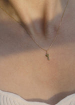 Solid 14k gold necklace with a small key pendant on a person wearing a light-colored top.