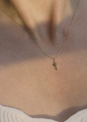 Solid 14k gold necklace with a small key pendant on a person wearing a light-colored top.