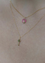 Two solid 14k gold necklaces with a key pendant and a round pendant on a person's neck from sb studio yeg.