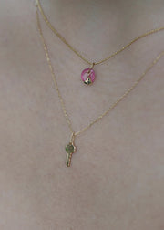 Two solid 14k gold necklaces with a key pendant and a round pendant on a person's neck from sb studio yeg.