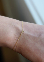 Close-up of a person's wrist wearing a delicate 14k yellow gold bracelet from SB Studio.