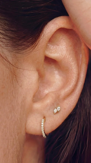 SB Studio Cecilia huggie hoop earrings in 14k gold with prong-set white topaz worn on a model's earlobe.