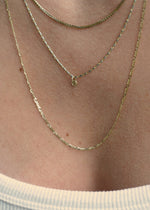 Sb Studio 14k yellow gold button charm pendant worn on a delicate layered cable chain necklace.