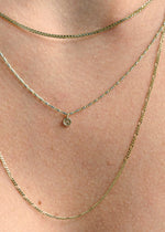 Sb Studio 14k yellow gold button charm pendant worn on a delicate layered chain necklace.