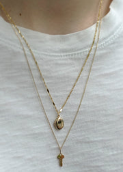 sb studio 14k gold honeybee locket and key pendant layered on a delicate cable chain necklace.