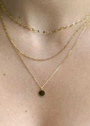 Sb Studio  14k yellow gold Love Token charm pendant layered with delicate gold chains on a woman's neck.