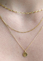 Sb Studio 14k yellow gold Love Token charm pendant layered on a delicate gold chain necklace.