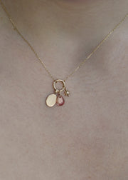 sb studio gold pendant necklace featuring a small engravable charm, a pink gemstone, and a tiny star charm.