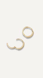 SB Studio Cecilia huggie hoop earrings in 14k yellow gold with prong-set white topaz stones.