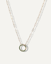 SB studio solid 14k gold paperclip chain necklace featuring a circular charm holder embellished with small green gemstones.