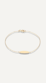 The Sparkle Bar 14k yellow gold signet charm bracelet with a delicate beaded chain and engravable oval charm.